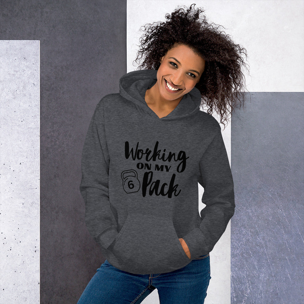 Dark heather colored unisex hoodie featuring the phrase 'Working on my 6 Pack' in black font. This cozy hoodie is perfect for the gym or evening walks.