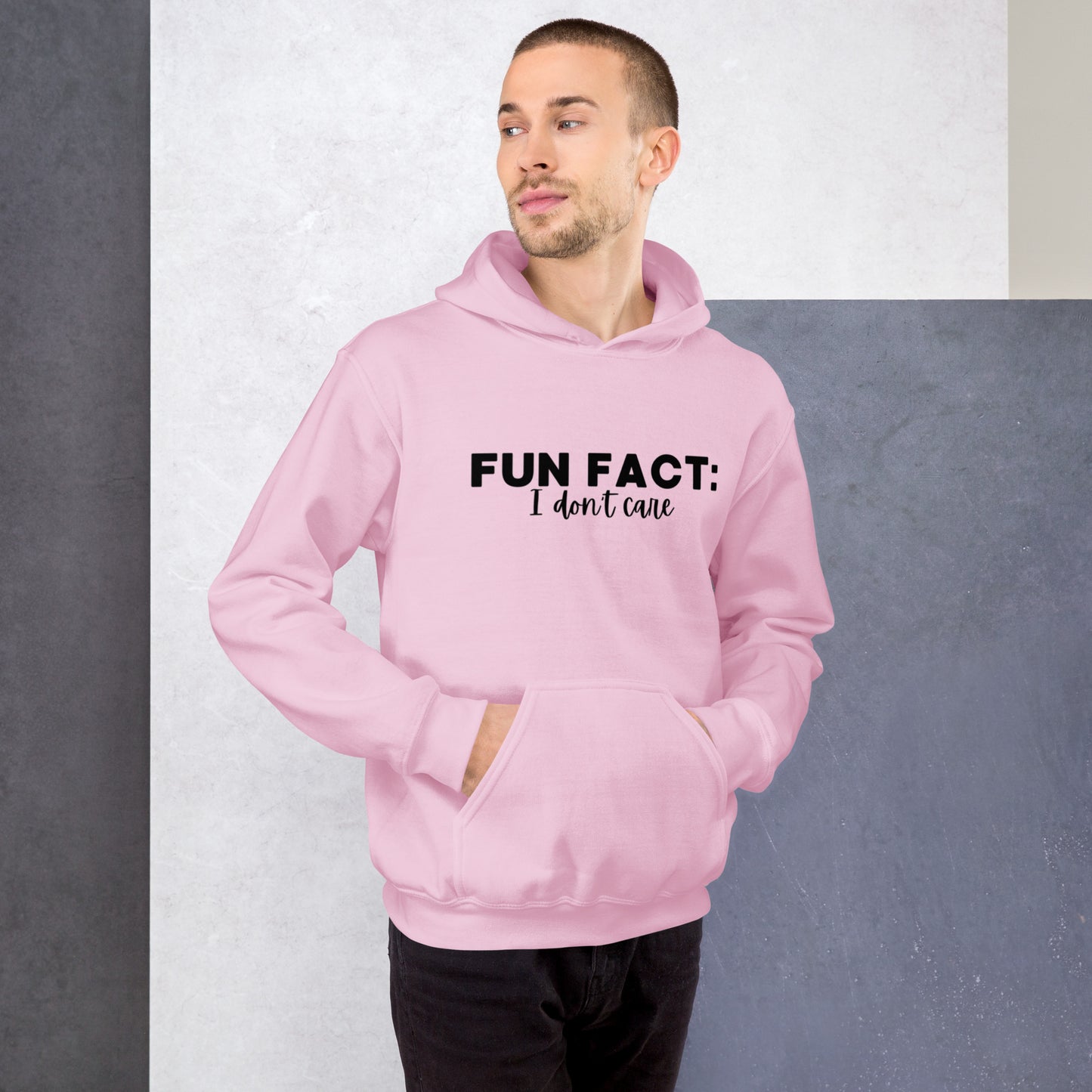 Light pink colored unisex hoodie featuring the phrase 'Fun Fact: I Don't Care' in bold black writing on the front above the front pouch pocket