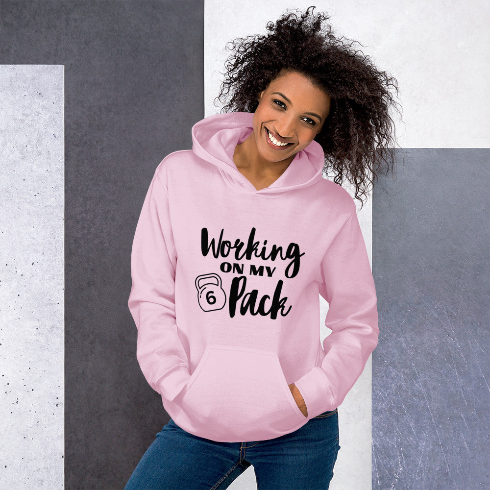 Light pink colored unisex hoodie featuring the phrase 'Working on my 6 Pack' in black font. This cozy hoodie is perfect for the gym or evening walks.