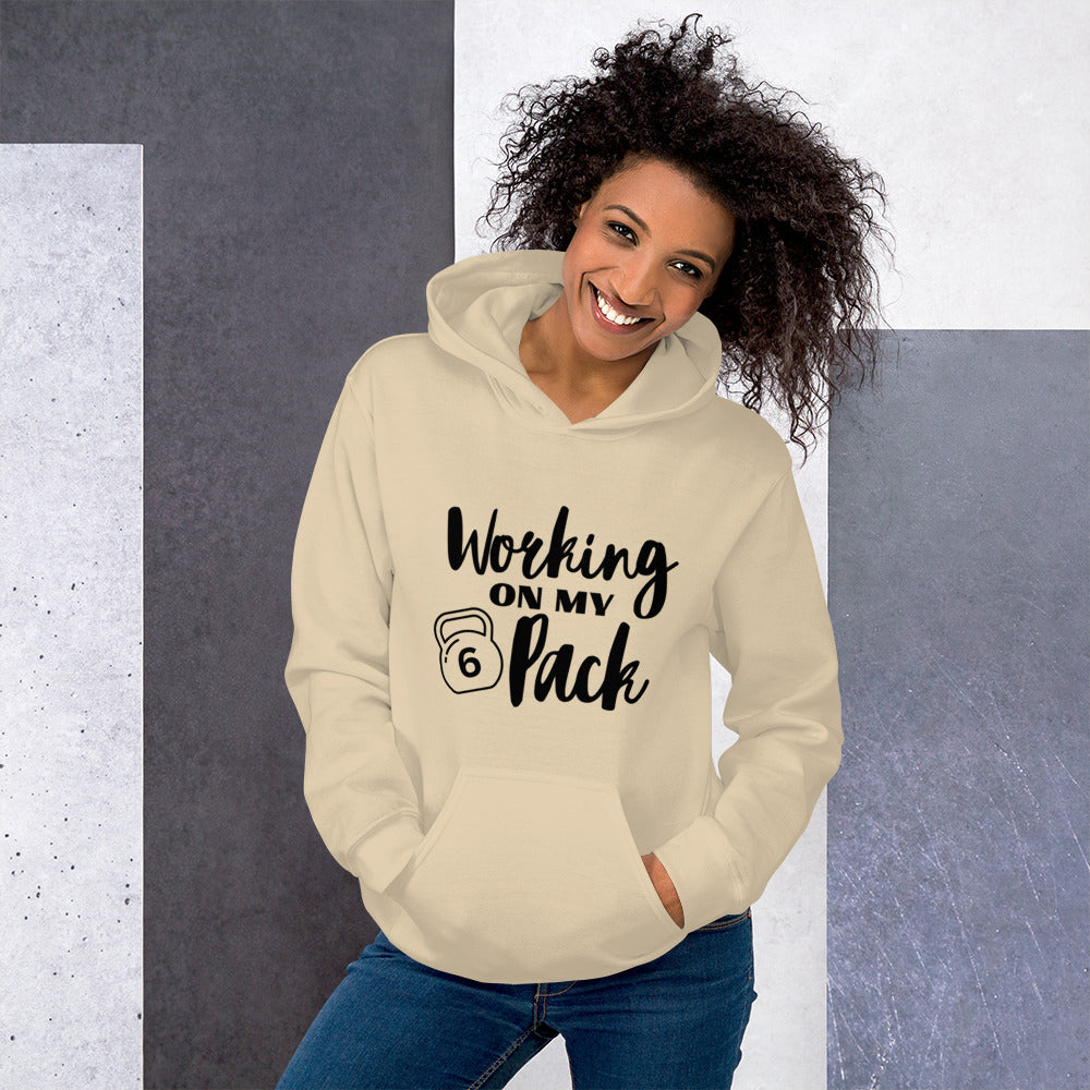 Sand colored unisex hoodie featuring the phrase 'Working on my 6 Pack' in black font. This cozy hoodie is perfect for the gym or evening walks.