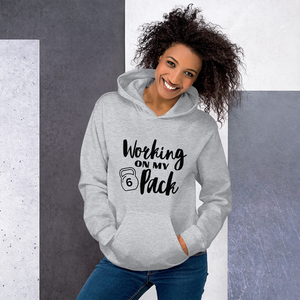 Sport grey colored unisex hoodie featuring the phrase 'Working on my 6 Pack' in black font. This cozy hoodie is perfect for the gym or evening walks.